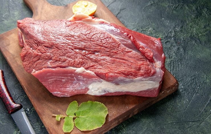 Vista de cerca de carnes rojas crudas frescas limón sobre tabla de cortar de madera marrón