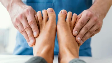 Vista frontal del terapeuta osteopático masculino comprobando los dedos de los pies del paciente bótox