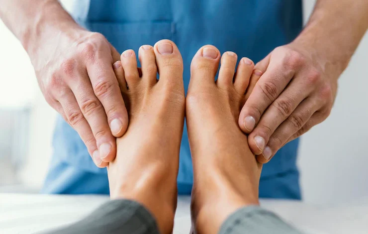 Vista frontal del terapeuta osteopático masculino comprobando los dedos de los pies del paciente bótox