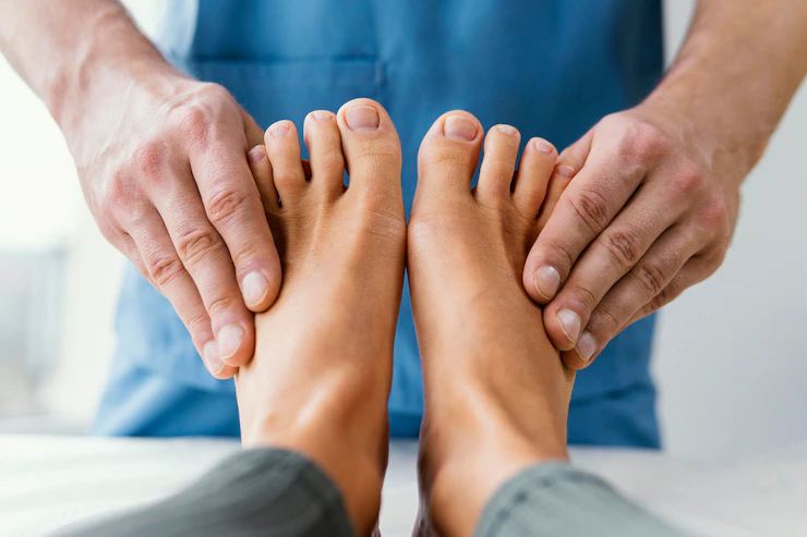 Vista frontal del terapeuta osteopático masculino comprobando los dedos de los pies del paciente bótox
