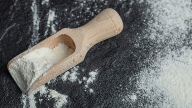 Una cuchara de madera con harina en negro. f&eacute;cula