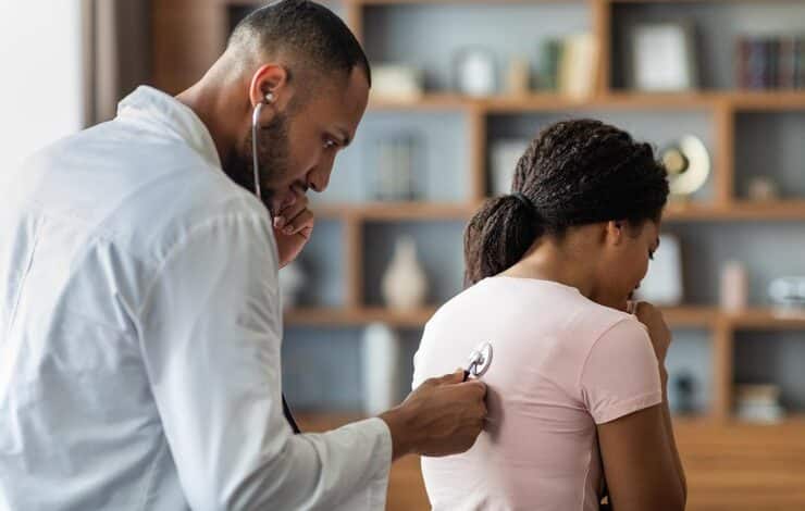 Hombre &aacute;rabe m&eacute;dico general revisando los pulmones de una mujer enferma con estetoscopio c&aacute;ncer