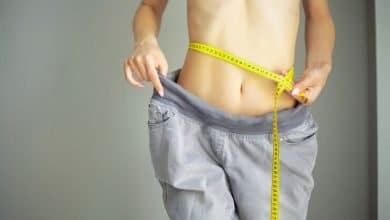 Manos midiendo la cintura con una cinta. mujer delgada y sana en su casa