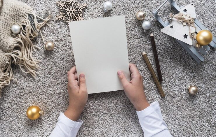 Foto las manos del niño escriben una carta en una hoja de papel vacía concepto de navidad y año