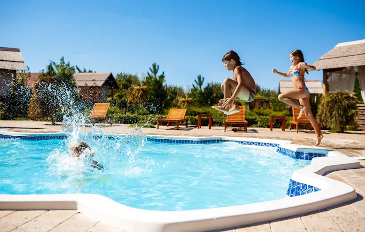 Niños alegres regocijándose, saltando, nadando en la piscinas