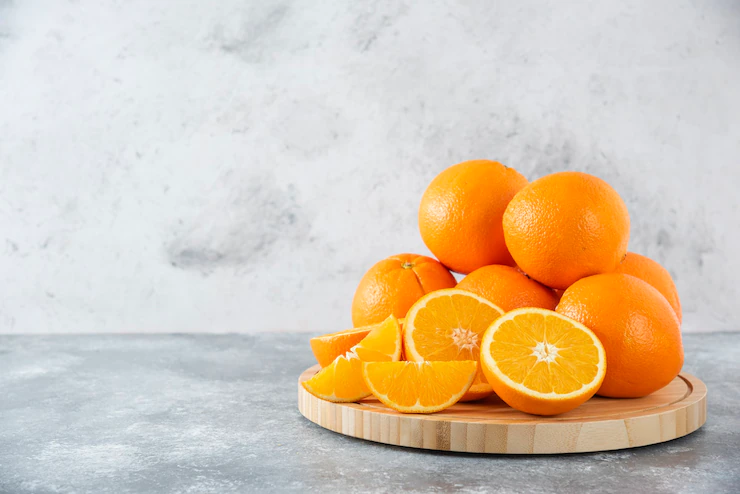 Una tabla de madera llena de jugosas rodajas de fruta naranja en la mesa de piedra vitamina C