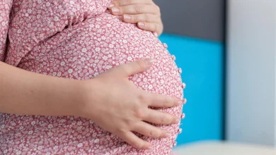la mujer embarazada cogidos de la mano en la panza en el consultorio quintillizos