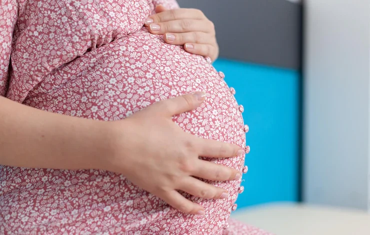 la mujer embarazada cogidos de la mano en la panza en el consultorio quintillizos