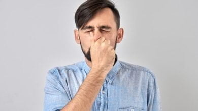 joven tapándose la nariz para evitar el olor disgustado pellizca la nariz y la boca con los dedos hipo