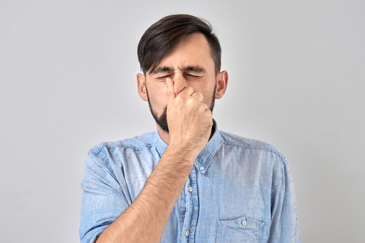 joven tapándose la nariz para evitar el olor disgustado pellizca la nariz y la boca con los dedos hipo