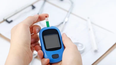 mano que sostiene un medidor de glucosa de sangre que mide el azúcar de sangre