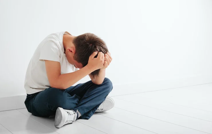 Un niño con depresión está sentado en el suelo.