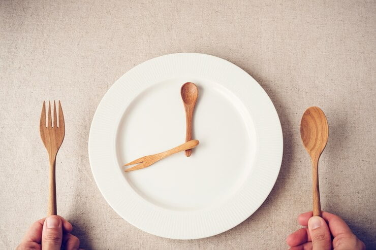 plato blanco con cuchara y tenedor, concepto de ayuno intermitente