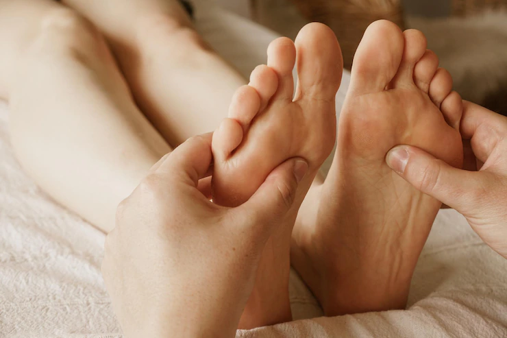 Primer plano de masajista masajeando los pies de una mujer masajes