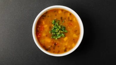 sopa de lentejas con ingredientes mixtos y hierbas en un tazón blanco.