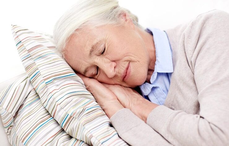 concepto de edad, relajación y personas - anciana feliz durmiendo en una almohada en casa dormir