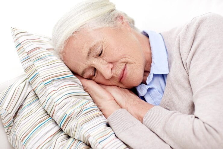 concepto de edad, relajación y personas - anciana feliz durmiendo en una almohada en casa dormir