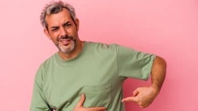 hombre cauc&aacute;sico de mediana edad aislado sobre fondo rosa con dolor de h&iacute;gado, dolor de hernia