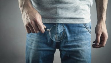 que sostiene la lupa en los pantalones vaqueros test&iacute;culos