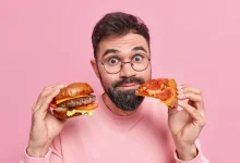 hombre comiendo hamnburguea y pizza reducir niveles de triglicéridos
