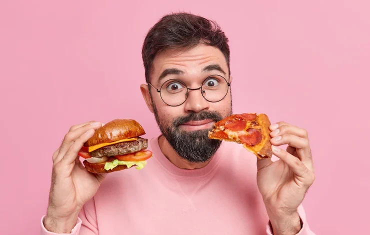 hombre comiendo hamnburguea y pizza reducir niveles de triglicéridos