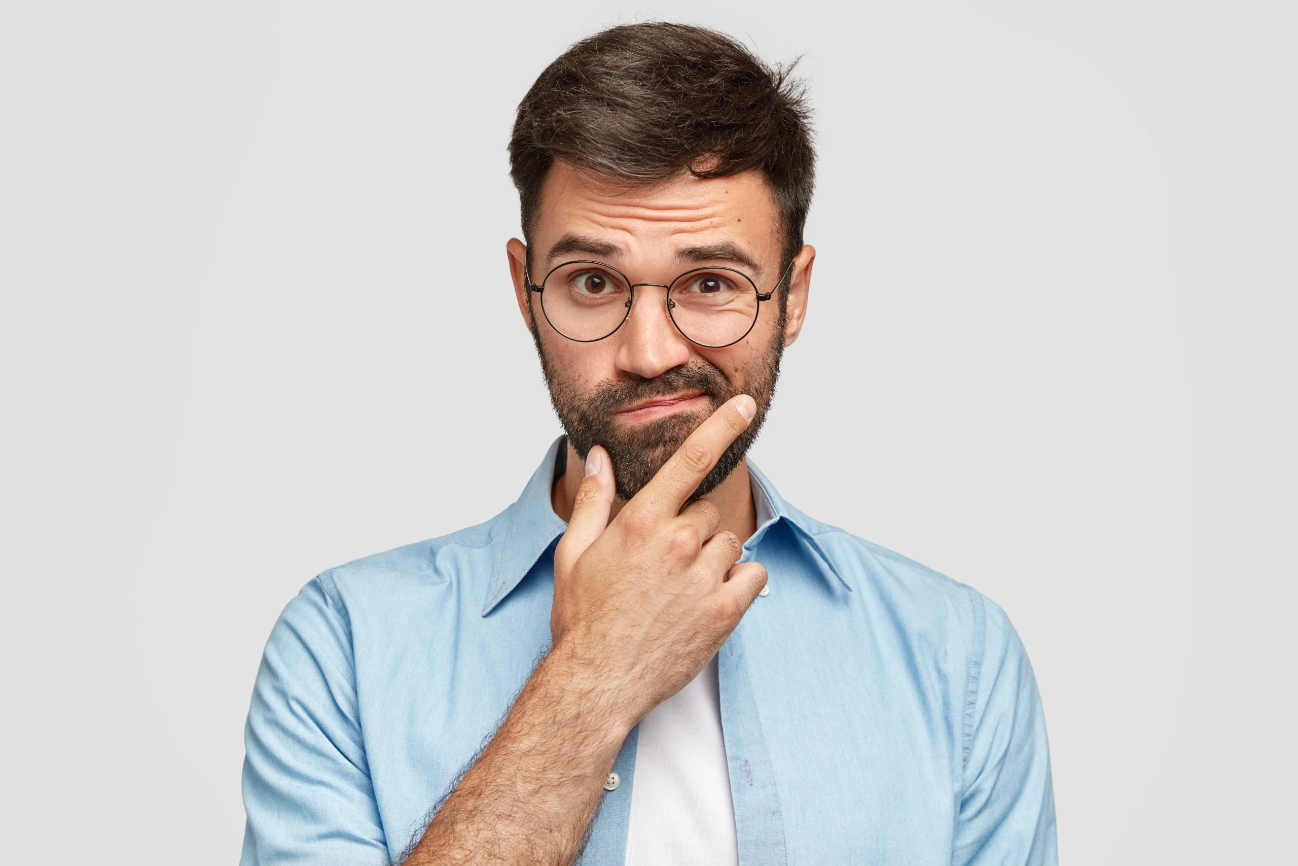 hombre europeo sin afeitar vacilante con barba espesa, sostiene la barbilla mucosidad en las heces