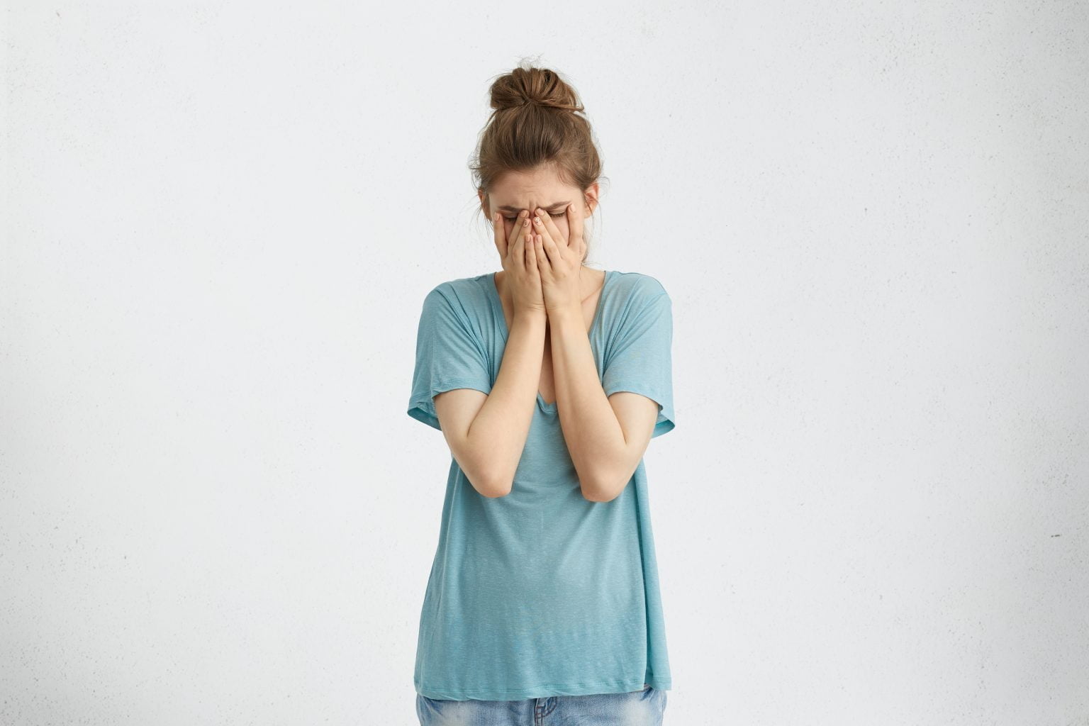 mujer desanimada decepcionada con moño de pelo vistiendo una camiseta suelta decepción