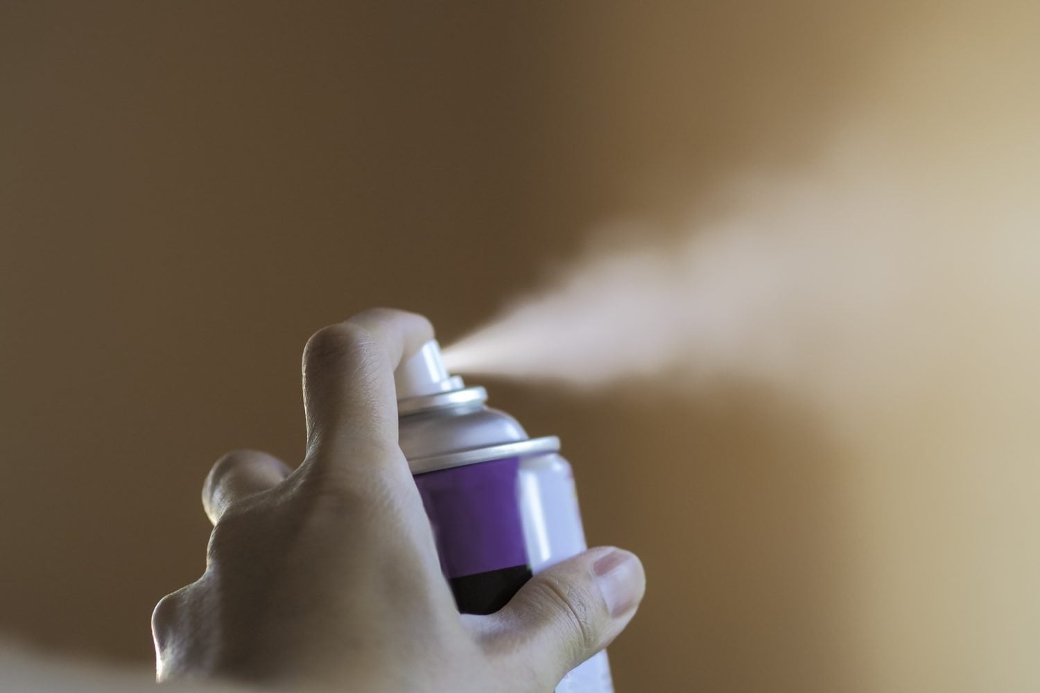 mano oprimiendo el dispensador de un desodorante en aerosol