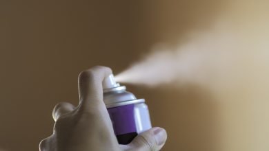 mano oprimiendo el dispensador de un desodorante en aerosol