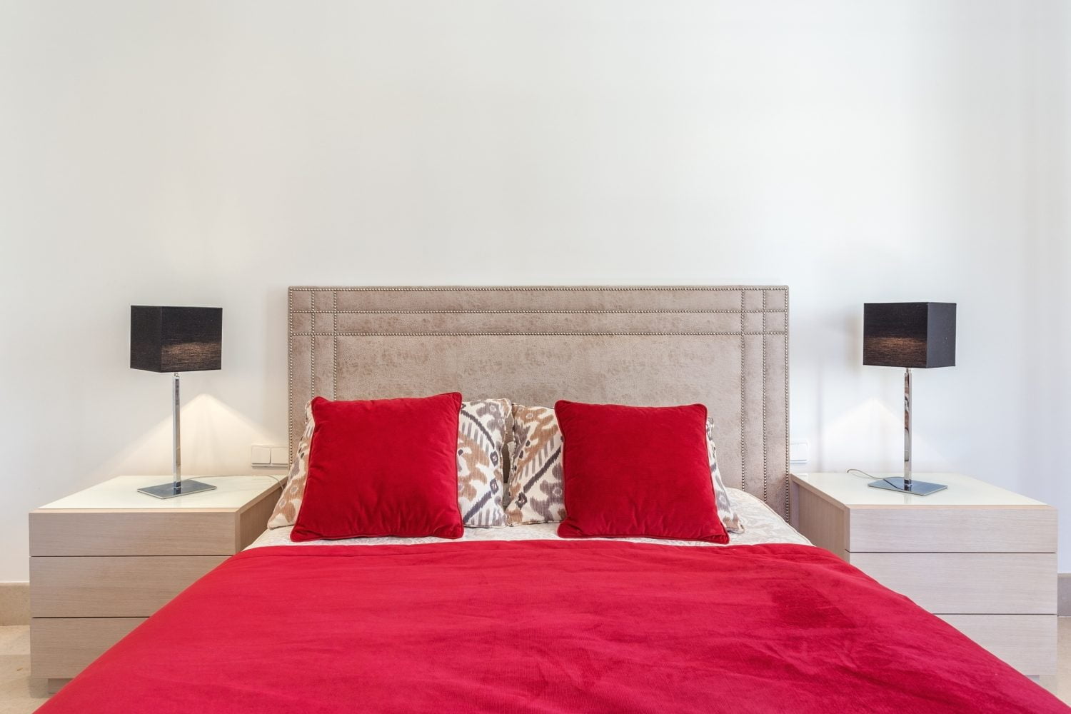 elegante dormitorio moderno con cama y almohadas rojas