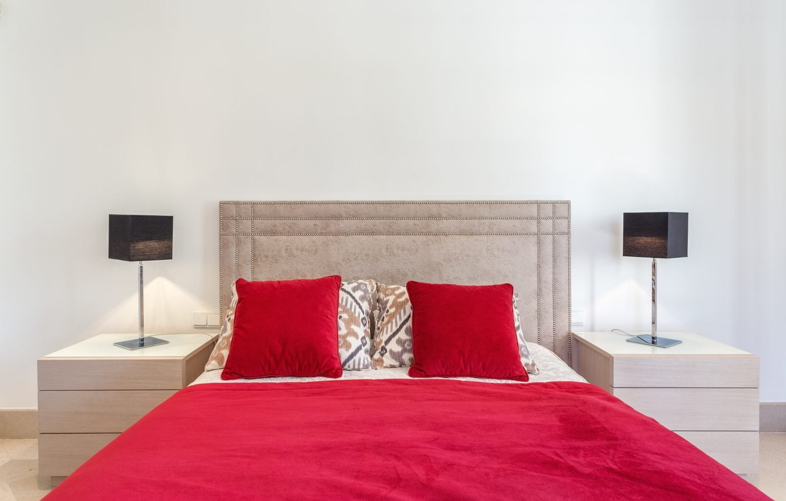 elegante dormitorio moderno con cama y almohadas rojas