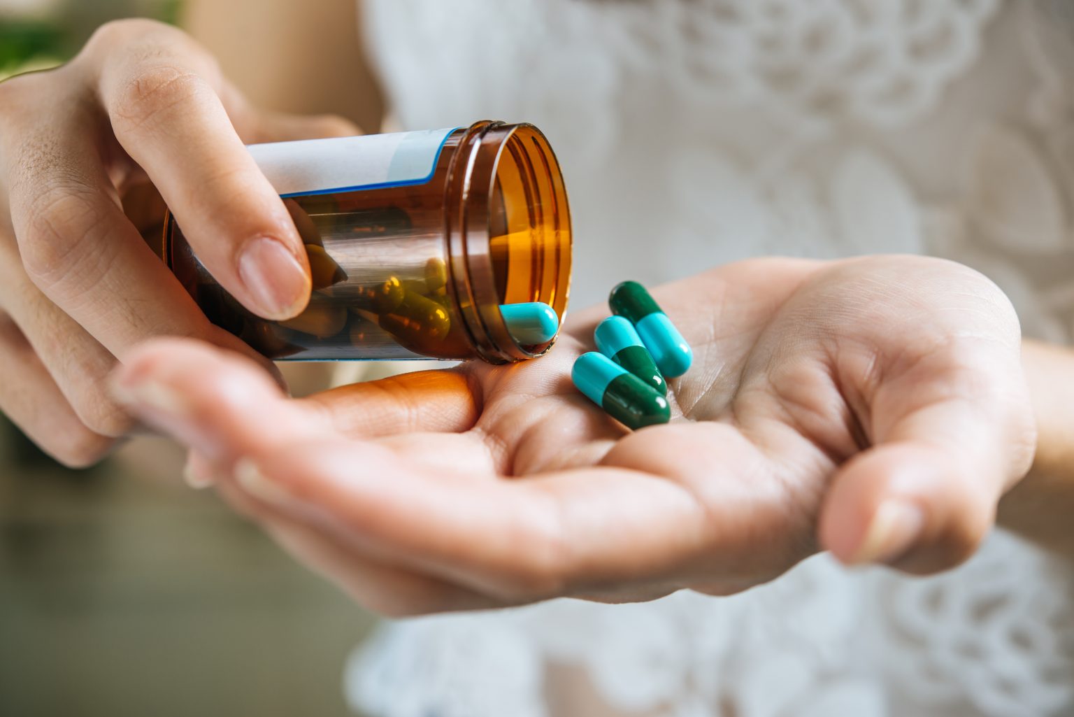 mano de mujer vierte las pastillas de la medicina fuera de la botella antibióticos