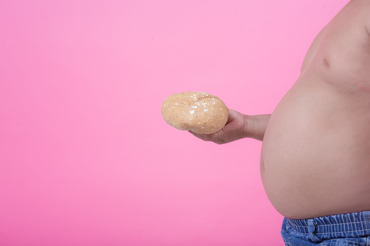 niño obeso que tiene sobrepeso sobre un fondo rosa.