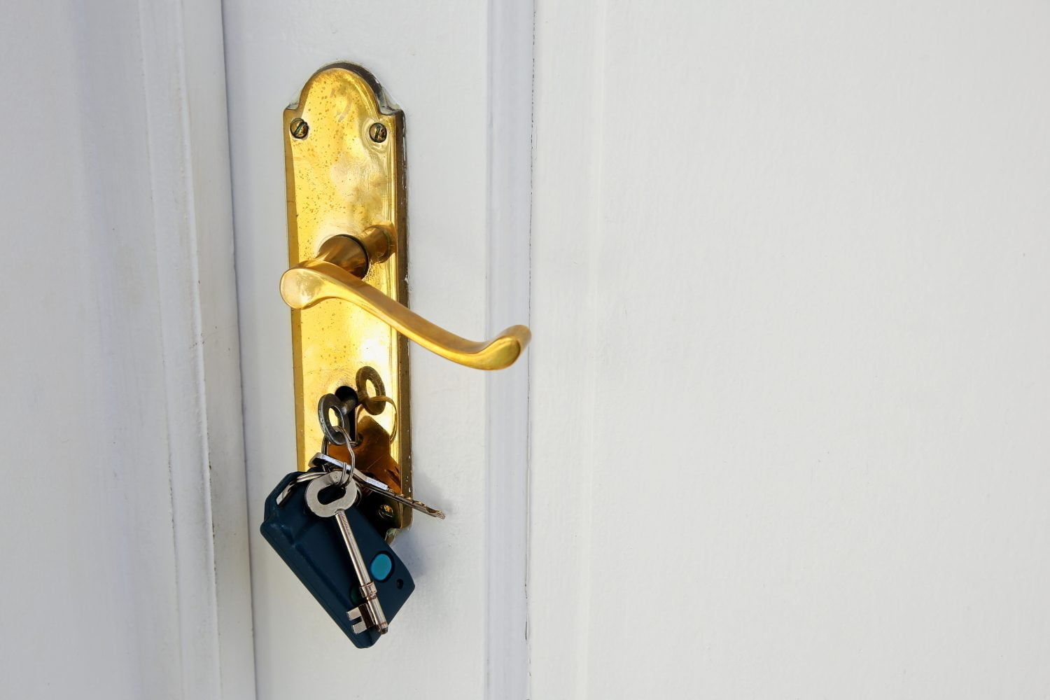pomo de oro con llaves en una puerta blanca
