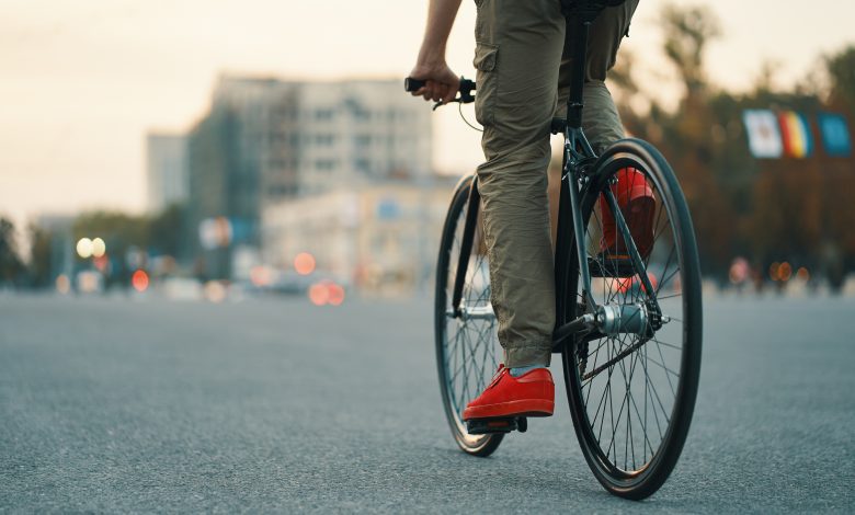 primer plano de las piernas del hombre casual en bicicleta clásica en la carretera