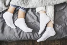 piernas masculinas y femeninas en calcetines debajo de una manta en una cama